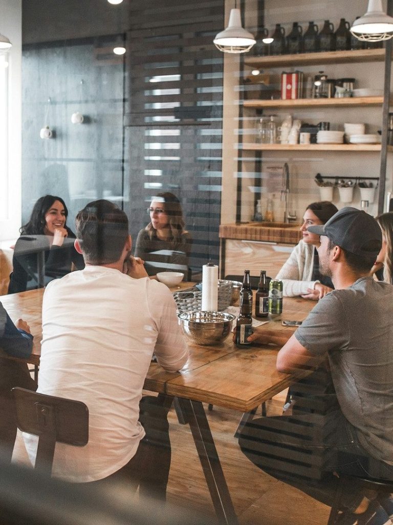 Reunión de personas alrededor de una mesa en un ambiente moderno y acogedor.