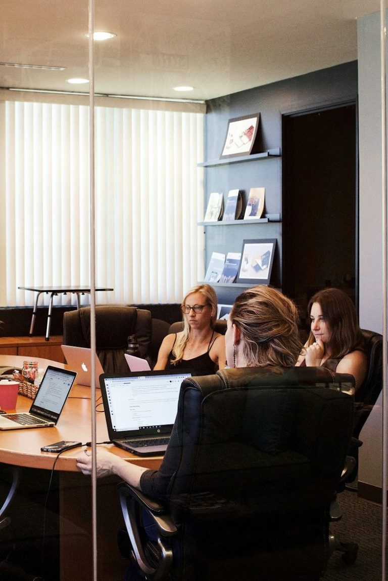 Cuatro personas trabajando en una sala de reuniones con laptops y documentos.
