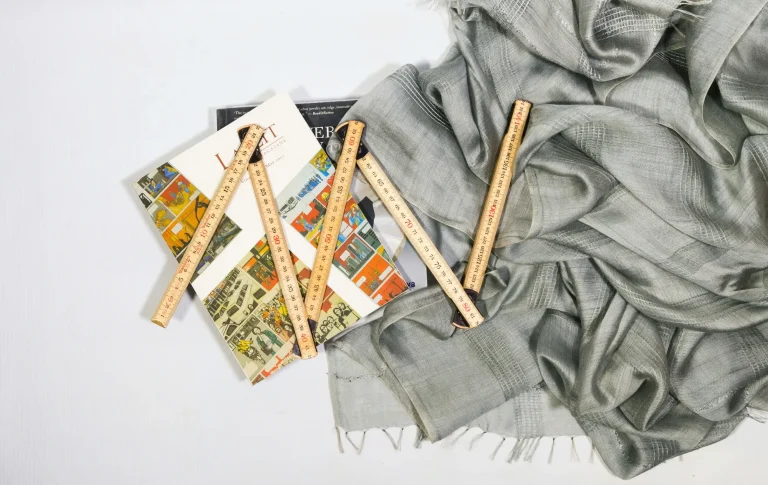 Cuatro reglas de madera sobre un fondo de telas y revistas coloridas.